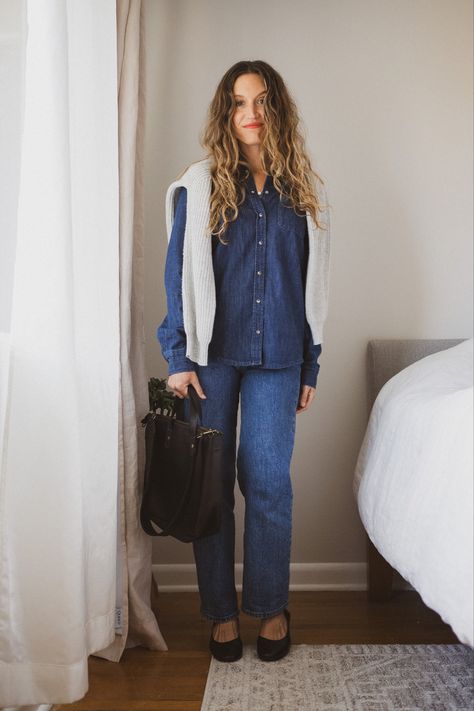 Ashley wearing a dark wash denim shirt with a gray sweater over the shoulders, dark Wash straight leg jeans, black heels, and a black tote bag Fall Dark Wash Chambray Denim Top, Fall Washed Blue Denim Shirt, Dark Wash Collared Relaxed Fit Denim Top, Unstructured Medium Wash Denim Shirt, Casual Chic Fall Outfits, Casual Chic Fall, Chic Fall Outfit, Dark Wash Chambray Button-up Denim Top, Chic Fall Outfits