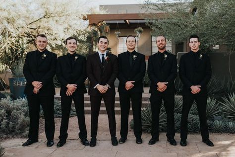 This Black, Burgundy, and Gold Desert Botanical Garden Wedding is a Total Showstopper Gold And Black Groomsmen Attire, Black On Black Mens Wedding Suit, Fall Wedding Groomsmen Attire Black, Groomsmen In All Black Suits, Groomsmen All Black Suit, All Black Suit Wedding Groomsmen, Blacked Out Groomsmen, Black And Gold Bridal Party Attire, Groomsmen Black On Black