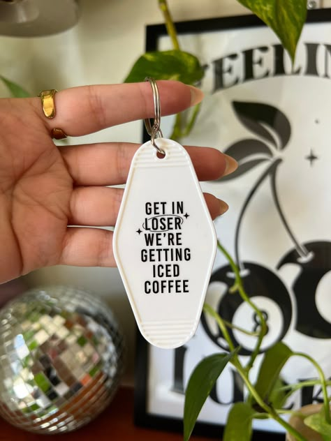 "Introducing our motel keychain with a playful twist: \"Get in loser, we're getting iced coffee.\" Inspired by the iconic movie quotes and everyday adventures, this keychain adds a touch of fun to your keys. It's the perfect accessory for coffee enthusiasts!" Coffee Inspired Gifts, Coffee Koozie, Gifts For Coffee Lovers, Keychain Sayings, Coffee Shop Merch, Cricut Gifts, Iced Coffee Gifts, Iconic Movie Quotes, Girly Car Accessories