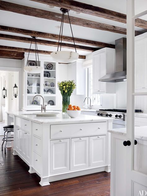 Reclaimed-oak beams shelter the kitchen, which is equipped with a Viking hood and cooktop and Calacatta gold marble counters. Ivory Kitchen, Casa Clean, Tudor Style Homes, All White Kitchen, Classic Kitchen, White Kitchen Design, Tidy Kitchen, Kitchen Trends, Large Kitchen