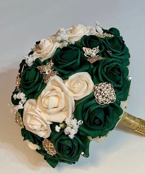 This beautiful 11 inch Emerald / Hunter's Green bouquet has Ivory / Champagne real touch roses and some babies breath. Scattered throughout are gold crystal brooches and butterflies. The handle is trimmed in gold diamond wrap. Real touch roses are a perfect choice for Quinceanera and Wedding because the blooms will look fresh the whole day. If they appear to be a little crushed in transit, just place in a heavy glass or vase (no water, please!) and they will get back to their original shape in no time. Bouquets are mailed using USPS Ground Advantage which takes approximately 2-5 business days for delivery. If you need your bouquet sooner, please let us know and we will ship via USPS Priority Mail - the difference will be given to you at time of receiving your bouquet order.  Thank you for Quince Bouquet, Emerald Green Quinceanera Theme, Green Quinceanera Theme, Gold Wedding Bouquets, Quinceanera Bouquet, Gold Wedding Flowers, Bouquet Green, Long Beach Ny, Green Wedding Bouquet