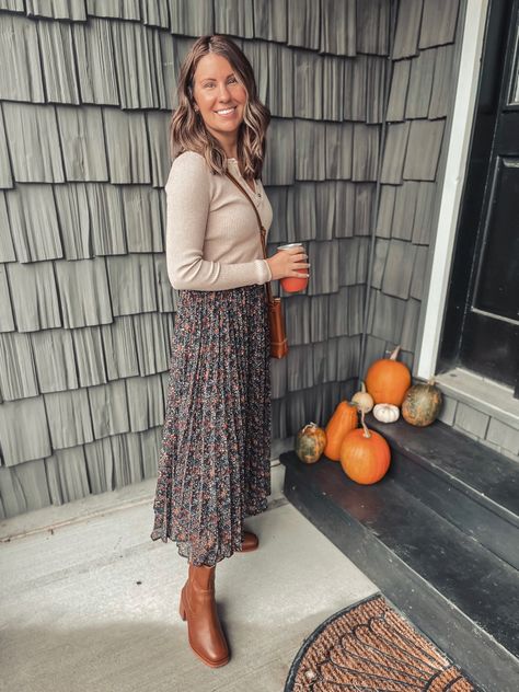 A woman wearing a tan henley top, black floral skirt, brown crossbody bag, brown block heel boots. Fall Floral Skirt Outfits, Midi Skirts With Boots, Midi Skirt Autumn Outfit, Chelsea Boots Skirt Outfit, Fall Viscose Midi Skirt, Mustard Midi Skirt Outfit, Sweater And Midi Skirt Outfit, Fall Bohemian Skirt With Floral Print, Everyday Fall Midi Skirt