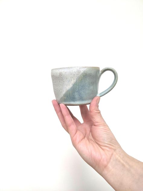 A unique mug. This was hand thrown on a potter's wheel, part dried and then trimmed around the base. Fired for the first time. Then dipped in speckled creamy grey glaze and overlapped with a delicate, pale blue-green, with gorgeous colour variation. Fired again at over 1200C. Suitable for the dishwasher and microwave. Food safe glazes.