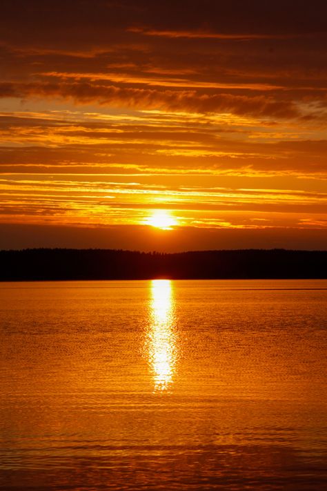 Intense sunset with orange glow over natural lake in Finland. Light reflections of sunset over water surrounded by hills Sunset Over Water, Art Assessment, Moon Board, Ducks Unlimited, Orange Sunset, Lake Water, Water Reflections, Sun And Water, Lake Como