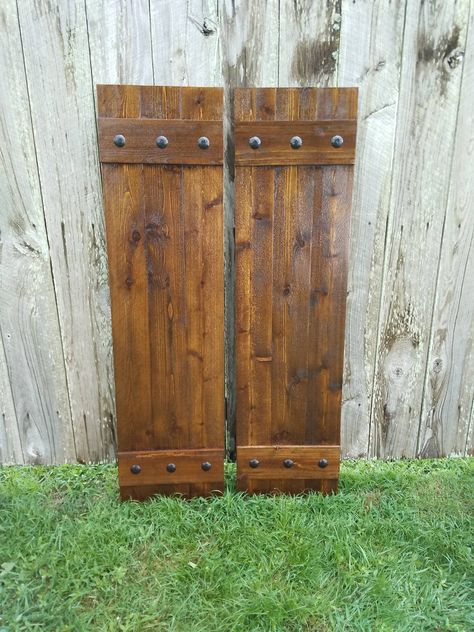 "2 \"Board N Batten\" style Rustic Cedar Shutters, with Black Clavos nails for exterior use. Color in this listing: Early American. Each shutter is made with 5/8\" thick boards. The \"Board N Batten\" style is made with 3 vertical boards joined together with 2 horizontal boards as shown. There are 6 Clavos Nails on each shutter - 3 on the top batten and 3 on the bottom batten. CONSTRUCTION - Our shutters are made with rough cut western cedar wood. They are strongly built as shown being nailed, g Exterior Cedar Shutters, Wood Shutters Exterior, Nails Board, Shutter Hardware, Rustic Shutters, Cedar Shutters, Diy Shutters, Cedar Boards, Rustic Hardware