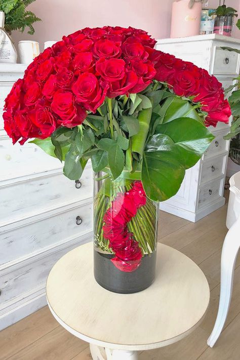 As if to say, “I’m all yours and you’re all mine,” this breathtaking floral arrangement features two bouquets of passionate red roses artfully placed side by side. A romantic gesture that can make your love swoon, it comes in a tall, elegant glass vase filled with black sand and rose petals. This stunning arrangement has a total of 10 dozen red roses. Natural Flower Centerpieces, Red Floral Arrangements, Romantic Flower Arrangements, Gifts For Partner, Beautiful Roses Flowers, Red Flower Arrangements, Romance Flowers, Red Rose Arrangements, Roses And Pearls