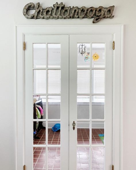 Glass paned French doors leading into the sun room of our Chattanooga house. We used the room as a playroom. The tile floor made clean up easy and it was nice to be able to shut the door. The metal sign was a fun touch. Playroom Sliding Door, Playroom With Pocket Doors, French Door Playroom, Playroom With Sliding Glass Doors, Dollhouse French Doors Diy, Small Playroom, Shut The Door, French Doors, Clean Up