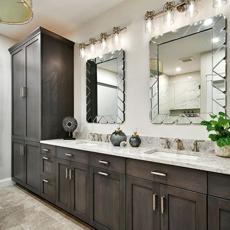 The dark wood cabinets in this bathroom contrast beautifully with the light walls and countertop. Luxurious lighting and large mirrors enhance the look and feel of this space, while the accessories give a small pop of color. #KnoxvilleInteriorDesigner #InteriorDesign #HomeDecor #BathroomDesign Bathroom With Dark Wood Vanity, Dark Brown Bathroom Cabinets, Bathroom With Dark Cabinets, Dark Stained Cabinets, Dark Brown Bathroom, Luxurious Lighting, Light Walls, Dark Counters, Large Mirrors