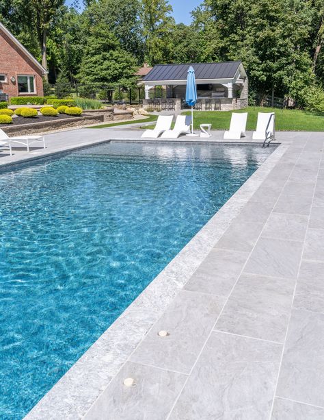 Dive into the beauty of this pool, meticulously adorned with our best-selling Pietra Grey marble copings paired flawlessly with the subtle veining of our Moon porcelain pavers. This combo is nothing short of iconic, where the striking white veining of the Pietra Grey marble harmoniously complements the understated veining of the pavers. Together, they create a poolside panorama that radiates elegance, sophistication, and timeless beauty. Marble Pool Coping, Pool Pavers And Coping, Pool Coping And Tile, Pool Scapes, Pool Patio Pavers, Portugal Garden, Pietra Grey Marble, Portugal House, Pool Makeover