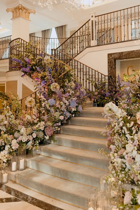 Descend into elegance at Adare Manor, where the grand staircase is adorned with ombre florals, transitioning from purple to white, offering a breathtaking entrance to the wedding dinner. Grand Wedding Ceremony, Whimsical Classy Wedding, Small Luxurious Wedding, Wedding Venue Manor House, Fancy Wedding Aesthetic, Ethereal Mansion, Wedding Venue Mansion, Manor House Wedding Decorations, Floral Wedding Venues