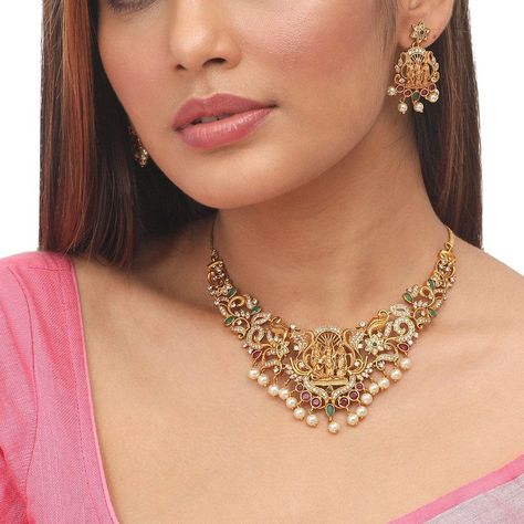 This statement Tarinika antique necklace is a real eye-catcher. Ram Parivar motifs and floral motifs are aligned together to form a beautiful choker necklace. It is crafted with CZ stones and clustered pearls on the antique gold-plated finish to give a unique contrast look. An extraordinary piece made by the highest level of craftsmanship. Style it on linen or silk sari for a vintage look. Specification- Length: Necklace -11.5 cm, Earrings - 13 cm Weight: Necklace - 41 gm, Earrings - 13gm 100% S Gold Choker Temple Necklace For Festive Occasions, Gold Necklace Set Antique Choker, Traditional Gold Plated Choker For Wedding, Festive Gold Choker Temple Necklace, Traditional Gold-plated Choker, South Indian Temple, Indian Jewelry Set, Earring Indian, Gold Necklace Wedding