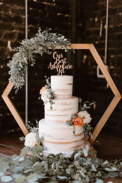 If you're looking for a modern twist on a classic wedding treat, this show-stopping three-tier naked white wedding cake on a geometric cake stand is sure to be the highlight of your special day. Not only will this gorgeous cake be a showstopper, it will also add a touch of sophistication to the celebration with its intricate diamond design. With layers of tender buttercream and moist white sponge, this cake is sure to be a hit with your guests at the reception. Erin Morrison Photography Hexagon Wedding Cake Topper, Wedding Cakes Stands Ideas, Modern Boho Wedding Backdrop, Cake Stand Backdrop, Wedding Cake Arch Stand, Octagon Centerpiece Wedding, Honeycomb Wedding Decor, Wedding Hexagon Centerpieces, Hexagon Table Centerpieces