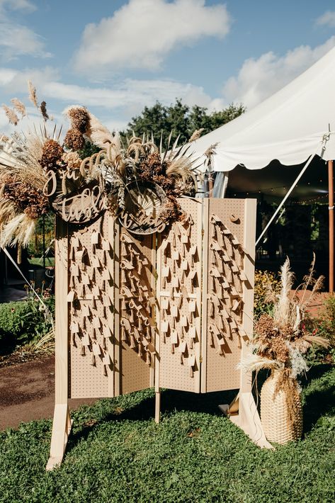 A wedding escort card display made out of pegboard and decorated with gorgeous dried florals. Your Table Awaits! Wedding Pegboard, Wood Palette Wall, Wedding Day Decor, Palette Wall, Reception Bar, Palm Leaf Wallpaper, Dried Florals, Boho Wedding Inspiration, Card Display