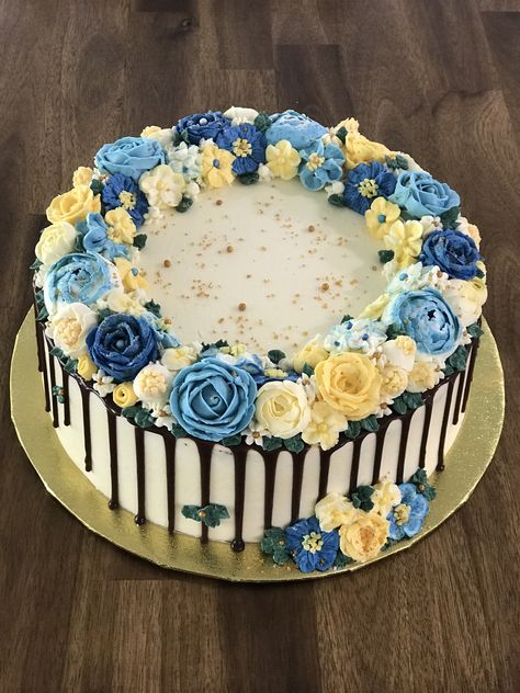 Floral Buttercream Cake. 2 x 10 inch layers using chocolate sponges. Chocolate custard filling. Buttercream coating with a dark chocolate drip. Various shades of dark blue, light blue, yellow and cream flowers. Finished off with white and gold sugar crystals and pearls. 10 Inch Cake Designs, Blue And Yellow Cake Ideas, Blue Floral Cake Birthday, Blue And Yellow Graduation Cake, Yellow And Blue Cupcakes, Blue And Yellow Birthday Cake, Blue And White Cake Design, Dark Blue Cake, Blue And Yellow Cake