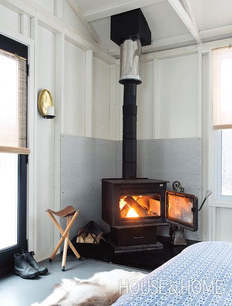 The Scandinavians are known for mastery of the modern farmhouse look. Here, a wood stove is updated with cool colors and light woods. | Design: Jay Hodgins | Photo: Alex Lukey Hygge Room, Wood Burning Stove Corner, Corner Wood Stove, Wood Stove Surround, Corner Stove, Wood Stove Hearth, Wood Burning Stoves Living Room, Cabin Fireplace, Cozy Rooms