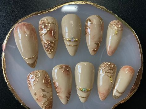 medium size almond shaped nails with delicate gold flower details. wear them and you will feel like having jewelry at the tip of your fingers. Floral And Gold Nails, Gold Flowers Nails, Almond Nail Shaping, Vintage Fall Nails, Gold Y2k Nails, Gold Almond Nails Designs, Ivory And Gold Nails, White And Gold Almond Nails, Vintage Nails 1950s