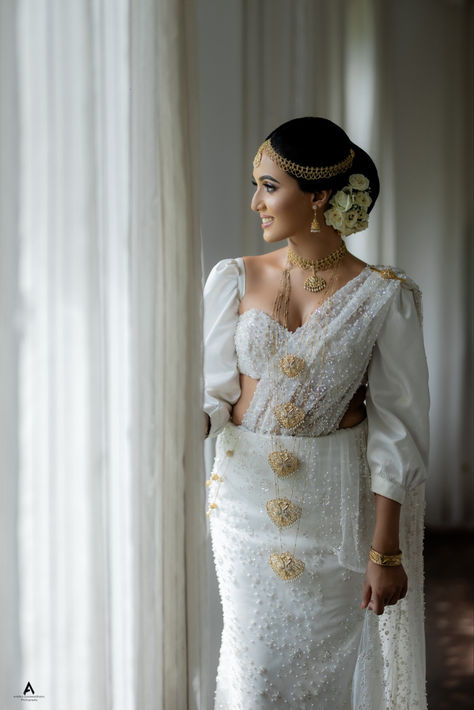 Discover the epitome of elegance with this off-white Kandyan bridal saree, adorned with intricate beadwork and paired with a modern blouse design featuring stylish cut-outs. Perfect for brides who desire a blend of tradition and contemporary fashion. Embrace the delicate balance of classic charm and modern sophistication for your special day with Lassana Saree's exclusive bridal collection.  #KandyanBridalSaree #BridalFashion #SriLankanBride #LassanaSaree Brides In White Saree, Modern Wedding Saree, Traditional Kandyan Bride, Modern Kandyan Saree Designs, Kandyan Bridal Saree, Modern Blouse Design, Modern Kandyan, Kandyan Saree, Kandyan Brides