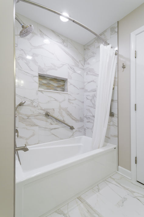 The client's main request was a bathtub for optimal relaxation. Our designer replaced the original walk-in shower with a deep tub and included a wall rail to make it more accessible. She then removed the soffits above the tub and sink to give the room height and make it feel open. She replaced the speckled shower surround with grey and white marble and installed a gold diamond shower niche. Our designer turned their bathroom into an oasis. Granite Shower, Bathroom Tub Shower Combo, Deep Tub, White Marble Bathrooms, Bathroom Tub Shower, Marble Showers, Large Vanity, Shower Niche, Shower Surround