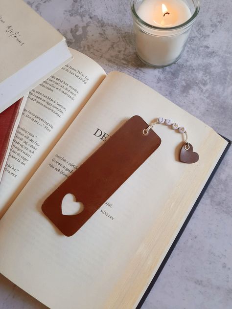 "Personalised leather bookmark in brown. This bookmark is handmade from genuine leather and is personalised with anything you can think of, names, dates, initials, etc. Dimensions: 3 x 10 cm (1,18\" x 3,93\") PERSONALISATION You can choose between capital letters and numbers. Maximum number of characters: 10 All items ship all over the world as STANDARD mail. If you would like *TRACKED DELIVERY* please select this shipping upgrade at checkout. The color may vary a bit from display to display." Leather Heart Bookmark, Homemade Leather Gifts, Things To Make With Leather Scraps, Leather Bookmark Ideas, Small Leather Crafts, Leather Bookmark Diy, Simple Leather Projects, Small Leather Projects, Bookmark Display