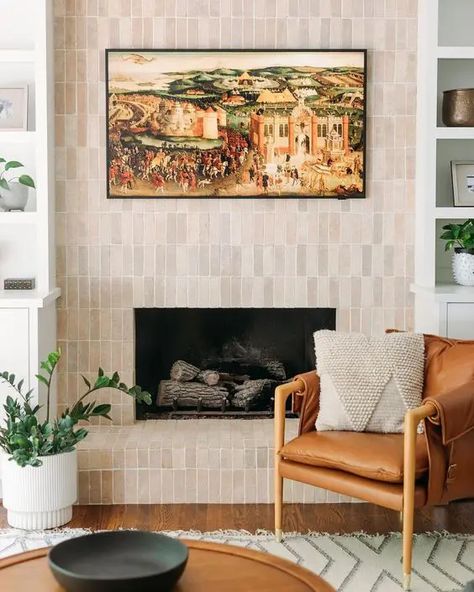 a fireplace clad with neutral skinny tiles is a stylish solution for a modern or mid century modern space Black Terracotta Tile Fireplace, Fireplace Zellige Tile, Tile Wall In Living Room, Natural Tile Fireplace, Spanish Tile Fireplace Ideas, Tiled Living Room Wall, Zellige Fireplace Surround, Zellige Tile Fireplace Surround, Modern Tile Fireplace Ideas