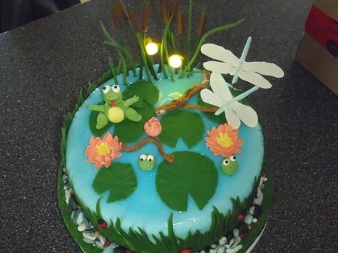 Gumpaste frogs, fireflies, dragonflies and flowers. Fondant grass,cat tails, lily pads and rocks, covered in blue fondant with piping gel water. The fireflies light up.  Entered in the fall fair 2011 and won 1st place, plus outstanding exhibit. This was my second fondant cake. First time making 3D figure. Cottage Core Recipes, Fccla Ideas, Running Cake, Pond Cake, Summer Birthday Cake, Flowers Fondant, Fantasy Cakes, Piping Gel, Fall Fair