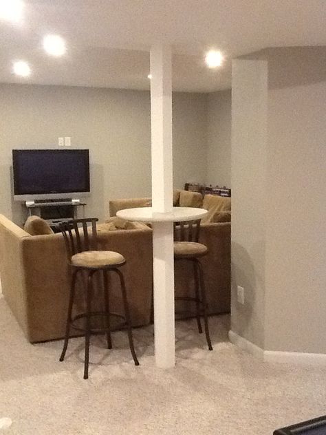 Basement support pole, bar height table.  Wood Basement pole wrap preconstucted cut at bar height and circle wood cut in half and fit around pole and glue all in place and paint Basement Column Ideas, Comfy Basement, Basement Pole Wrap, Basement Pole Covers, Basement Window Replacement, Basement Poles, Column Ideas, Basement Layout, House Basement