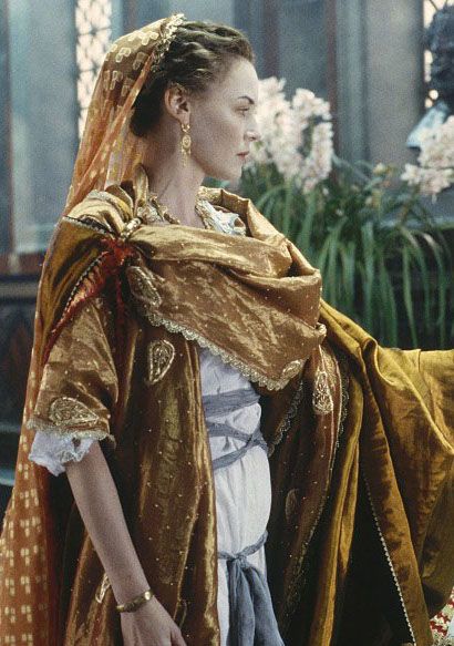 Lucilla's Rome Dress: A white silk v-neck underdress wrapped with a grey-blue sash. It has a scalloped trim along the neck and sleeves. The elbow length sleeves are unconnected at the top and held with silver clasps. Two layers of orange-gold wraps. The main is decorated with gold paisleys and embroidered with gold dots. The darker wrap drapes over the left arm along with the main wrap. Orange chiffon sits over her head attached to a gold laurel diadem by gold clips. Connie Nielsen, Gladiator 2000, Roman Clothes, Roman Dress, Period Movies, Roman Fashion, Costume Drama, Medieval Clothing, Movie Costumes