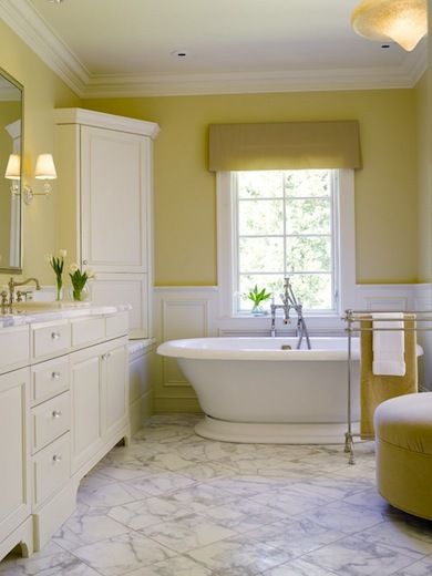 The peaceful quality of pale straw combined with white is undeniable. Elegant details in this serene setting include thick ceiling molding, glass knobs on the vanity, and a corner cabinet. The valance, upholstered ottoman, and bath towel carry the straw color around the room. Yellow Bathroom Walls, Yellow Bathroom Decor, Yellow Paint Colors, Gray Bathroom Decor, Bathroom Color Schemes, Lemon Sorbet, Bathroom Paint Colors, Paint Colors Benjamin Moore, Benjamin Moore Paint