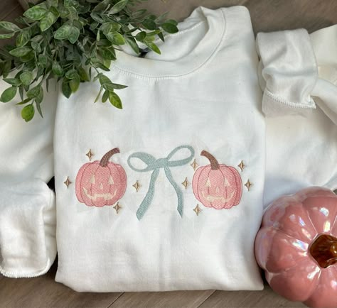 Get ready to embrace the "grandmillenial" trend this Halloween with our embroidered crewneck! Made from 100% cotton, this girly, stylish, and super comfy top adds a touch of whimsical charm to any Fall outfit. Our Grandmillenial Jack-o-lanterns are machine embroidered with the perfect shades of pink, blue and just the right amount of gold.  For best results wash inside out, cold water and lay flat to dry. Warm iron inside out if needed. Grandmillenial Halloween, Embroider Ideas, Boutique Shirts, Halloween Crewneck, Embroidered Crewneck, Birthday Wishlist, Simple Trendy Outfits, Comfort Colors Tee, Machine Design