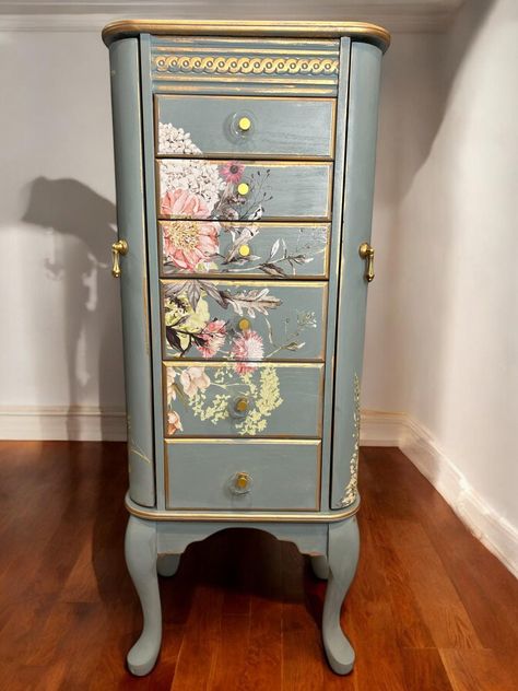 Large, absolutely stunning refinished jewelry armoire. I have never done this design before, and I am in love with it! Painted a greenish grayish blue, with a fabulous, neutral floral design on the front, top and sides. All of the drawers, which are lined in beautiful pink velvet, were decoupaged on both sides with a coordinating peach damask, making them extra special to open. The mirror, which opens from the top, has a delicate gold stencil on it. The sides open for hanging necklaces, showcasing gold script and stenciling. Understated gold highlights edge each of its five drawers and frame, as well as the raised embellishment across the top front. New circular glass and gold knobs were added to all the drawers and new gold pulls added to the doors that open. The entire piece was finished Jewelry Armoire Makeover, Standing Jewelry Box, Armoire Painted, Romantic Furniture, Painted Jewelry Armoire, Armoire Makeover, Furniture Blue, Jewelry Box Makeover, Standing Jewelry Armoire