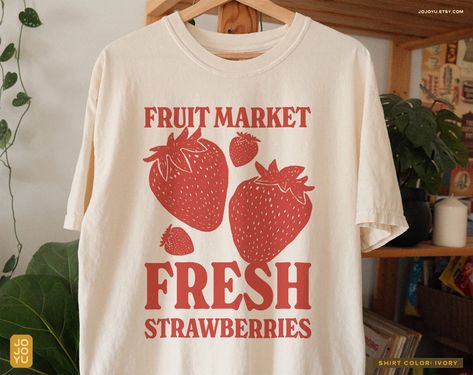 "Fruit Market Fresh Strawberries" Unisex T-shirt Design by jojoyu This item is made to order. If you want an oversized fit please size up! for reference, the model on the photo is usually a medium but wearing XL for an oversized fit. About the shirt: ◦ color: ivory ◦ relaxed fit  ◦ soft-washed, garment-dyed fabric ◦ double-needle stitching throughout the tee makes it highly durable  ◦ made with medium fabric (6.1 oz/yd²) consisting of high quality, 100% ring-spun US cotton for long-lasting comfo Fruit Graphic Tee, Strawberry Merch, Aesthetic Tshirt Design, Strawberry Clothes, Strawberry Tshirt, Strawberry Aesthetic, Retro Cottage, Fruit Shirt, Strawberry Shirt