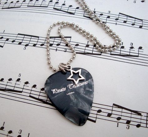 This cool necklace features a black pearloid Pirate Treasures London plectrum and star charm on a 20 inch silver tone ball chain, which fastens with a small lobster clasp.The necklace will arrive in an organza gift pouch and will be posted First Class within the UK and Royal Mail's international service worldwide.More music themed jewellery here http://etsy.me/1XiOoIyShop home page www.piratetreasures.etsy.com Guitar Picks Necklace, Band Merch Ideas, Black Guitar Pick, Cool Guitar Picks, Teacup Ring, Music Themed Jewelry, Cool Necklace, Saturn Necklace, Guitar Pick Necklace