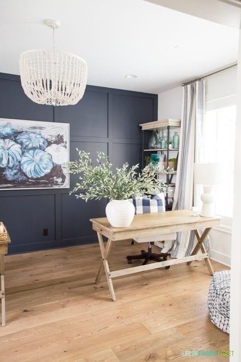 A beautiful home office with navy blue and white walls with white oak hardwood floors. The room is ready for fall with blue pumpkin abstract art, wood desks, a whitewashed wood bead chandelier, and a white vase full of olive leaves. #home #homedecor #falldecor #falldecorideas #office Blue And White Walls, Navy Accent Walls, Beautiful Home Office, Oak Hardwood Floors, Wood Desks, Bead Chandelier, Whitewashed Wood, Wood Bead Chandelier, Office Tour