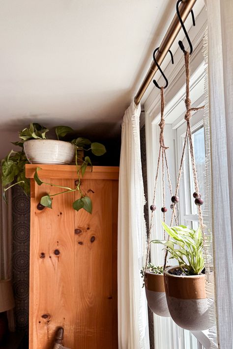 One of the easiest ways to update your bedroom decor is to add bedroom plants. Don't underestimate the power of plants!  Hanging plants from curtain rods is a fun way to add a touch of greenery and update your bedroom decor. Two of my favorite hanging plant varieties include pothos or string of pearls for a unique look. Check out our blog for more tips on updating your bedroom decor with plants. Your oasis awaits! Double Hanging Planter, Kitchen Plant Hanging Ideas, Plant Hanging From Curtain Rod, Hanging Plant In Living Room, Plants Hanging From Curtain Rod, Wall Hangers For Plants, Hanging Plants In Front Of Sliding Glass Door, Hanging Plants In Kitchen Ideas, Curtain Rod Plant Hanger Window