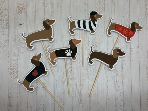 This is a cute set of 6 dachshund cupcake toppers featuring 6 different designs of sausage dogs.  Each cupcake topper measures 2.5 inches (5 cm) wide and 1.7 inches tall.  The toppers are handmade using high quality card and attached to a small wooden stick for easy insertion into the cake.  These party cake decorations will make any dachshund or sausage dog lover very happy.  The toppers are sold in packs of 6 or 12 with either one or two of each design included in the pack.  The toppers are sh Sausage Dog Cake, Dachshund Party, Dog Marketing, Dachshund Birthday, Dog Cake, Birthday Party Decor, Cute Sets, Sausage Dog, Birthday Theme