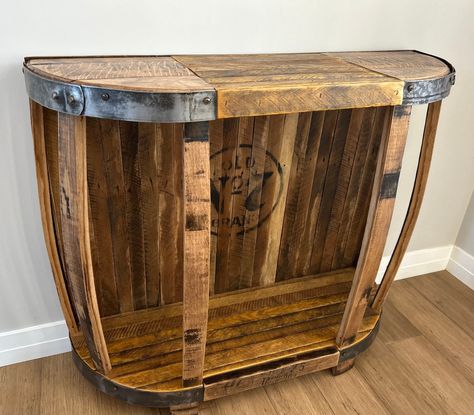 Rustic table created from whiskey barrel lids, staves, and tobacco lath make this table a unique combination to give you that one of a kind look. Table could be used as a entry, console table or small bar. Table top is a combination of reclaimed whiskey barrel tops and repurposed tobacco lath. Bottom shelf and solid back also consists of reclaimed tobacco lath. Each lath has its own color and texture due to the spearing and staining process in harvesting tobacco. Vertical supports are built using reclaimed whiskey staves. Steel rings that were once used in binding the whiskey barrels are polished and wrap both ends of the coffee table. Wood has been sanded and includes two coats of protective finish. Since every table is custom made from different whiskey barrels, size and color will vary Repurposed Whiskey Barrel, Wine Barrel Sink Bathroom, Barrel Sink Bathroom, Whiskey Table, Wine Barrel Sink, Small Bar Table, Barrel Lids, Bar Table Top, Barrel Sink