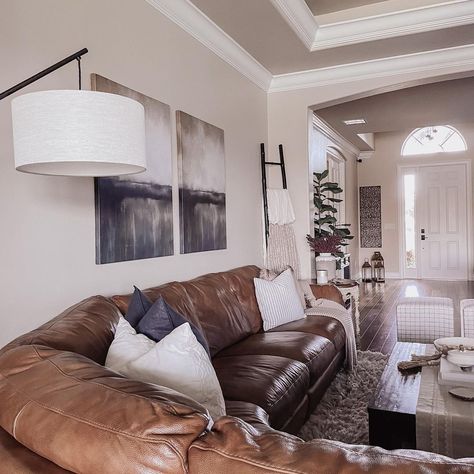 White trim outlines the beige walls of this living room, demonstrating a stylish way to incorporate neutrals. A brown leather sectional occupies much of the living room, creating a cozy appearance. The deep brown leather looks stunning beside the wooden coffee table. Brown Sectional Living Room, Leather Couch Decorating, Brown Leather Sectional, Leather Sectional Living Room, Sectional Living Room Decor, Dark Brown Couch Living Room, Brown Leather Furniture, Leather Couches Living Room, Brown Couch Living Room