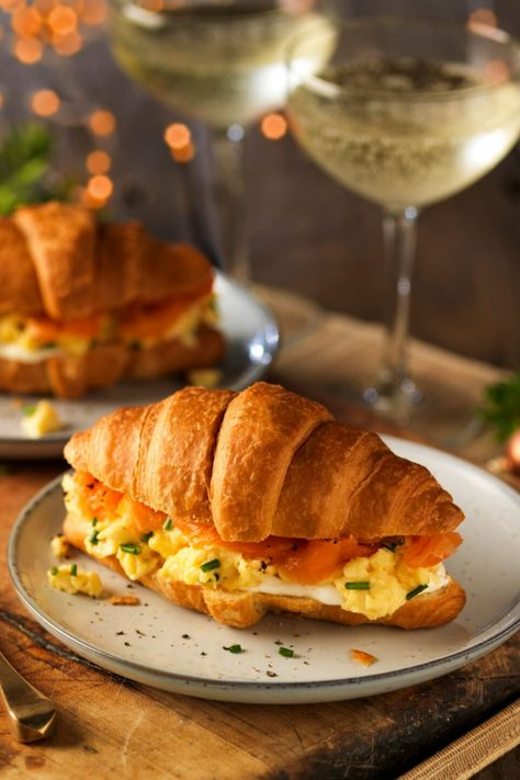 A croissant filled with scrambled egg and smoked salmon on a plate next to glasses of champagne. Egg Croissant, Crossaint Sandwich Breakfast, Special Breakfast, Filled Croissant, Croissant Recipe Breakfast, Salty Croissant, Savoury Croissant, Croissant Sandwich Breakfast, Egg Croissant Sandwich