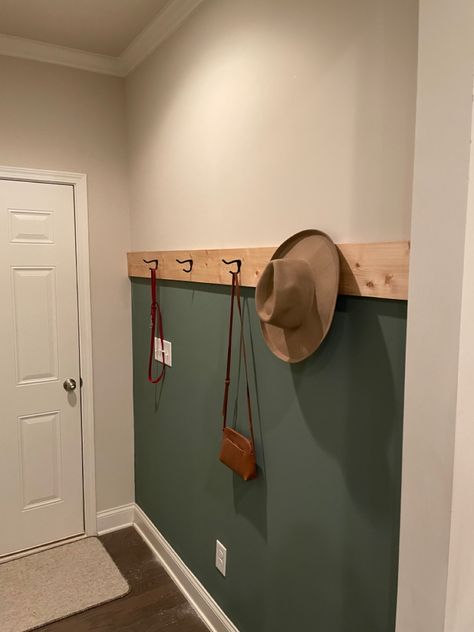 Green accent wall in entryway hallway/mud room with coat hangers and natural wood accent. Sage Green Entryway Wall Colors, Boho Green Accent Wall, Black White And Green Entryway, Green Accent Wall Hallway, Entrance Accent Wall Ideas, Green Mudroom Walls, Accent Wall With Hooks Entryway, Dark Green Entryway Walls, Green Wall Entryway