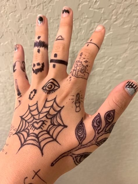 A hand with various doodles on it; including a heart-shaped spider web, a plant with eyes on the leaves, simple lava lamp and gun designs, and bands of different patterns on the fingers. Sharpie Hand Doodles, Simple Hand Tattoos, Pola Tato, Sharpie Doodles, Pretty Hand Tattoos, Finger Tattoo Designs, Sharpie Tattoos, Pen Tattoo, Hand Doodles