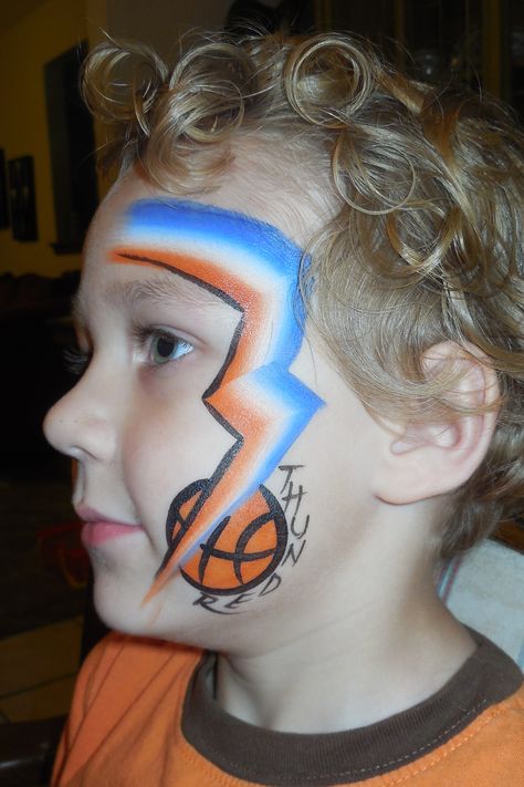 Thunder Basketball face paint- Fancy Faces OKC Face Paint Basketball, Facepaint Football, Basketball Makeup, Creative Face Paint, Fan Face Paint, Game Face Paint, School Spirit Face Paint, Face Paint Party, Faces Painting