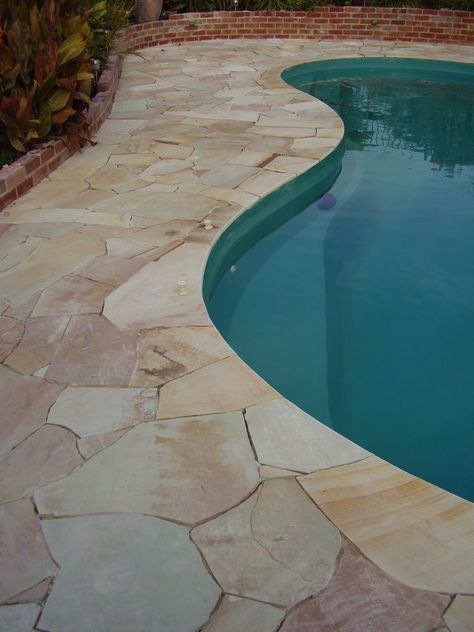 Curved Sandstone pool coping to blend with crazy paving. A continuous natural look #sandstone #pool #natural #poolcoping #kidneyshapepool Crazy Paving Around Pool, Crazy Pavers Pool, Pool Crazy Paving, Curved Pool Coping, Crazy Paving Pool, Sandstone Crazy Paving, Sandstone Courtyard, Flagstone Pool Coping, Pool Deck Stone