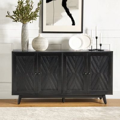 This mid-century-inspired sideboard brings plenty of vintage charm to your living room or dining area. The frame is made from engineered wood with a rustic finish, and it showcases a chevron-patterned inlay on the front with contrasting dark handles. With four doors and three adjustable shelves, it offers versatile storage solutions to accommodate your needs. The poplar wood legs with adjustable feet not only add to its retro appeal but also help keep it level. Designed to hold up to a 70" flats Black Sideboard Buffet, Mid Century Entryway, Sophisticated Casual, Wide Sideboard, Black Sideboard, Sideboard Furniture, Large Drawers, Sideboard Buffet, Grey Wood