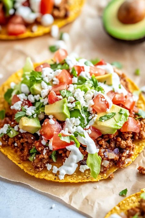 These easy Mexican tostadas are the perfect addition to any fiesta! Made with ground beef, refried beans, lettuce, tomato, cheese, and toppings, they're just too good! Low Cal Tostadas, Beef Tostadas Ground, Tostada Salad Bowl, Ground Beef Tostada Recipes, Ground Beef Tostadas, Ground Beef Refried Beans, Mexican Tostadas, Beef Tostadas, Tostada Recipes