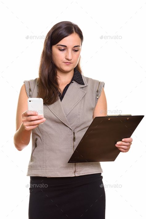 Portrait of young beautiful businesswoman using phone while holding clipboard by amazingmikael. Studio shot of young beautiful businesswoman isolated against white background #Sponsored #businesswoman, #phone, #holding, #Portrait Holding Phone Reference, Holding Clipboard, Holding Phone, Using Phone, Poses Reference, Human Poses Reference, Human Poses, Studio Shoot, Young And Beautiful