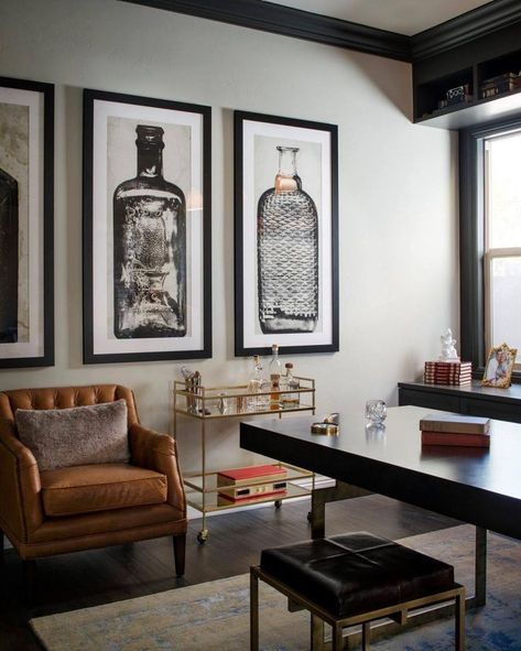 A glass-and-gold bar cart, brown leather armchair and oversized artwork of glass bottles give Mad Men-esque flair to this home office. Indigo Office, Home Office Masculine, Masculine Office Decor, Masculine Home Offices, Man Home Decor, Room Ideas Men, Room Decor For Men, Bachelor Pad Decor, Masculine Home Office