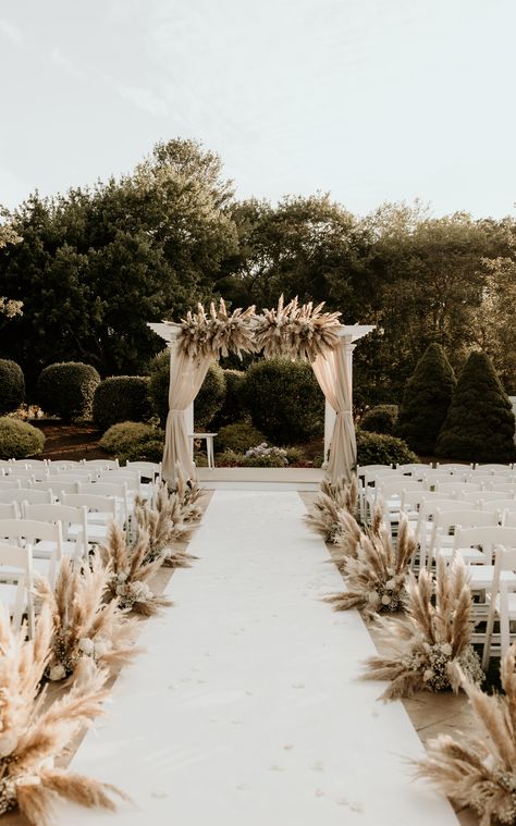 We're obsessed with this pampas grass wedding decor featuring arch draping, an aisle runner, and aisle decor. | Photography: Cami P Photography Pampas Grass Wedding Ceremony Aisle, Pampas Chair Decoration, Pampas Grass Wedding Aisle Decor, Pampas Down The Aisle, Wedding Arch Ideas Pampas, Wedding Ceremony Runner, Flowers Down The Aisle Wedding Outside, Pampas Grass Wedding Decor Isle, Outdoor Wedding Aisle Ideas Boho