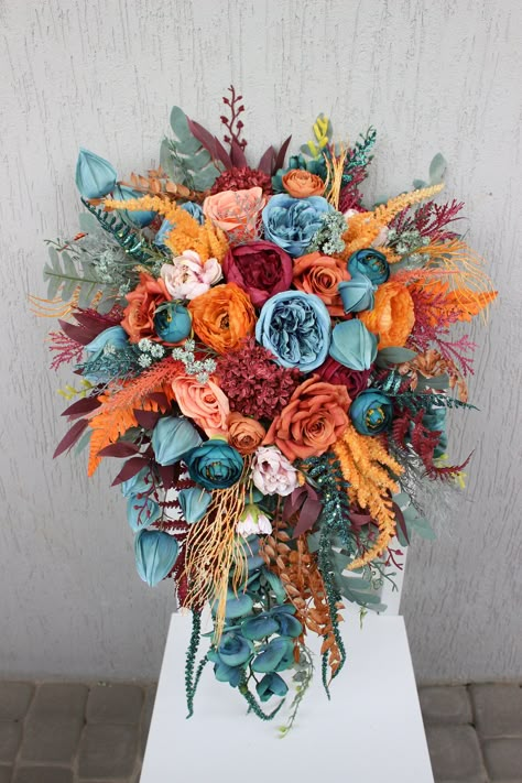 All the flowers and greenery is artificial and of high quality! Rustic Wedding Bride Bouquet, Teal Burgundy Orange Wedding, Unique Fall Wedding Centerpieces, Dark Teal And Burgundy Wedding Flowers, Wedding Flowers Blue And Orange, Flowers For October Wedding, Aztec Wedding Theme, Red Western Wedding, Teal And Orange Aesthetic