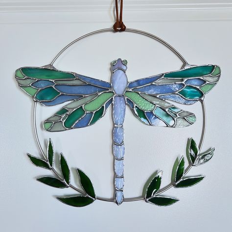 Stained glass dragonfly wreath custom made for a home warming gift 💙💚 As holiday season is approaching, keep small businesses in mind for gifts! I’m always happy to customize existing designs or create something unique for you! I forgot to measure the dragonfly but the hoop is 12in if that’s gives you a reference point 😅 (Copper restrip was added to the hoop connection points to ensure its structural integrity) #stainedglass #dragonfly #housewarminggift #custommade #handmade #homedecor Stained Glass Dragonfly Suncatcher, Dragonfly Stained Glass Pattern, Dragonfly Wreath, Stained Glass Dragonfly, Dragonfly Stained Glass, Glass Dragonfly, Stained Glass Christmas, Glass Projects, Stained Glass Projects