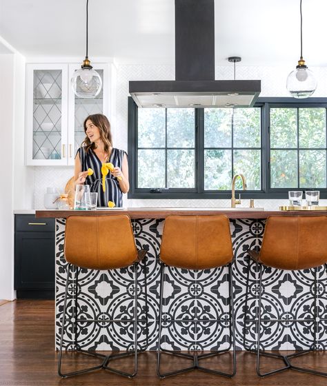 Keep It Simple  The kitchen island serves both as central gathering spot and style lodestar, with black-and-white cement tile that supplies the contemporary edge the couple was looking for. “Sometimes Spanish homes can feel weighty,” says Christina. “We wanted it to be young and fun.” In the kitchen, repurposed glass-front cabinets keep the mood light and airy, as does the new window the couple added over the sink. Wallpaper Kitchen Island, Cottage Kitchen Tiles, Wallpaper Kitchen, Spanish Style Homes, Spanish House, Kitchen Decorating, Diy Renovation, Kitchen Wallpaper, Kitchen Style